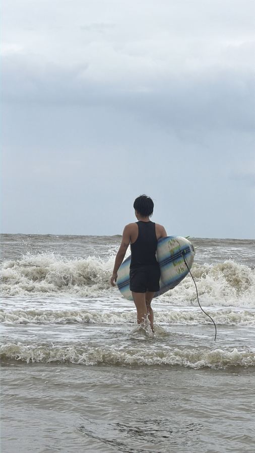 Junior Surf Club: a young surfer heading into the sea