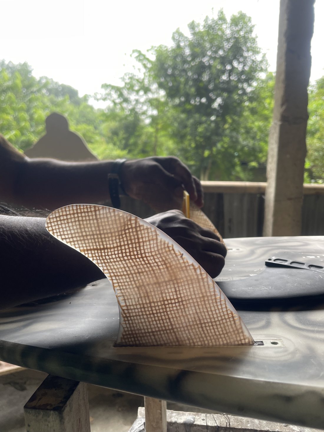 A hand-cast jute fin being fitted to a board