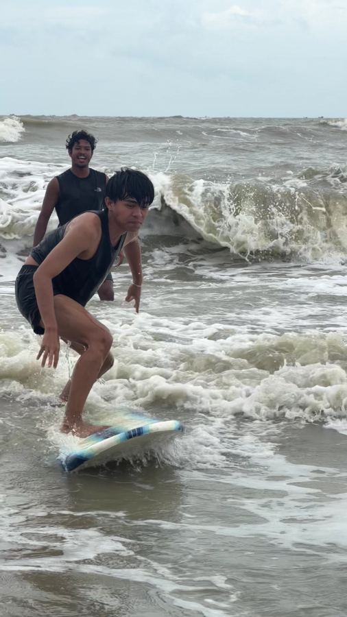 A Surf Hub coach behind a student standing up in the whitewater